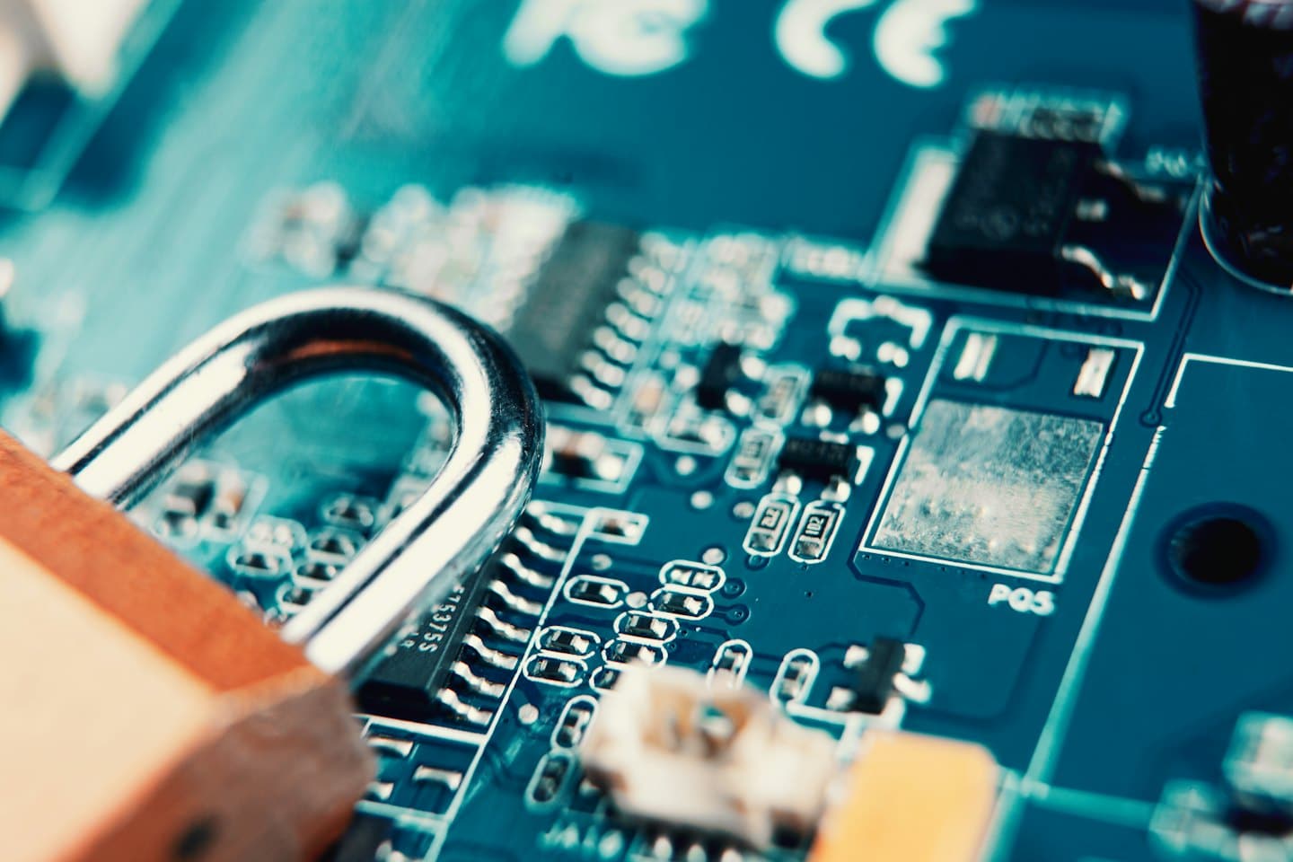 Brass padlock securing a blue-green circuit board.