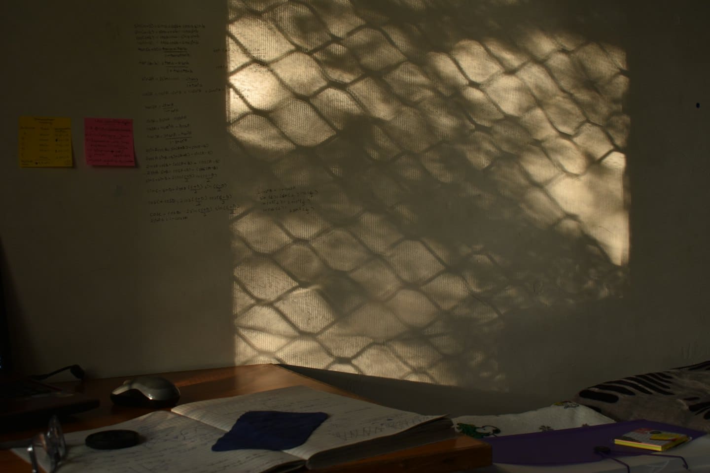 Mathematical formulas written on a desk notebook and wall.